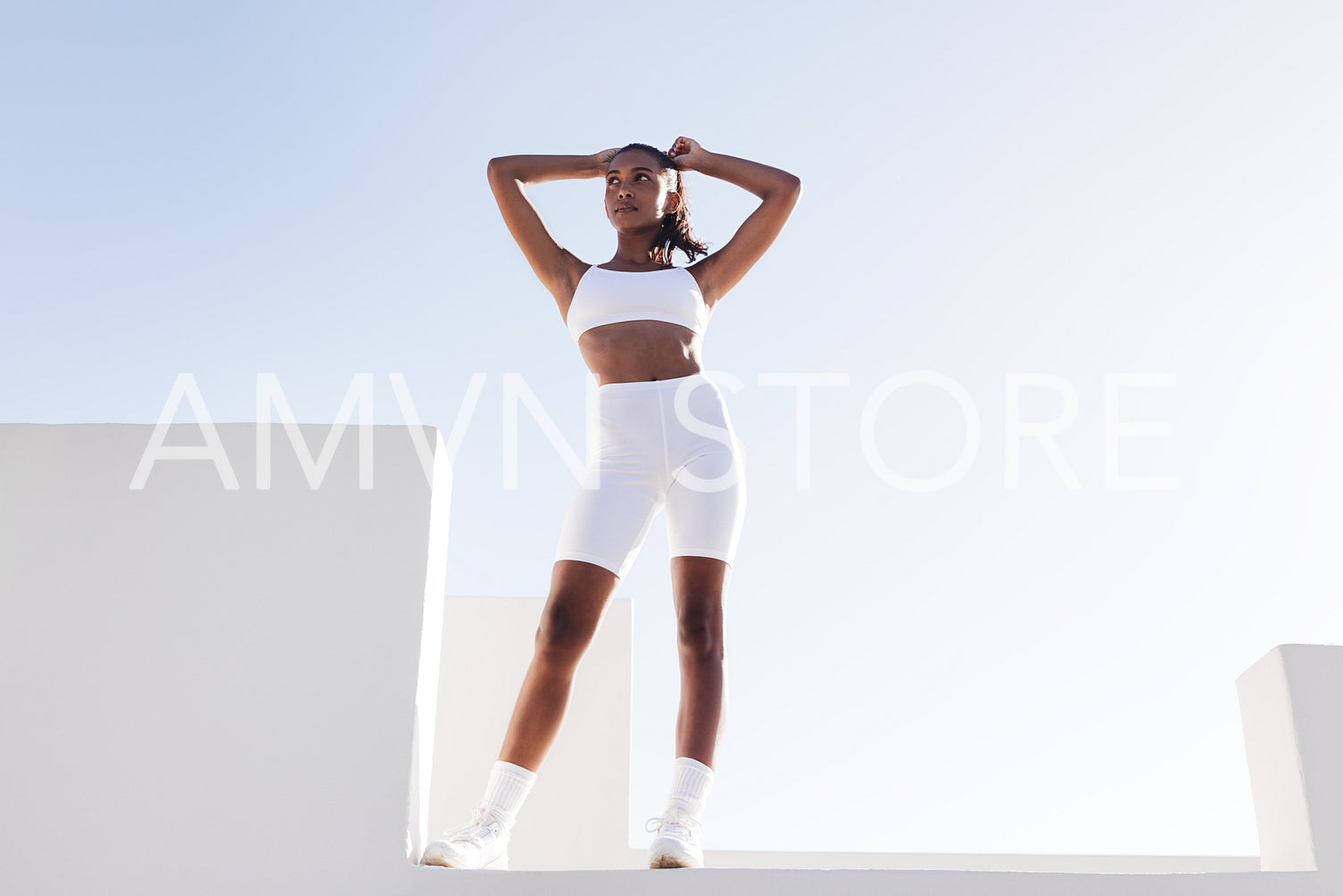 Full-length fitness female adjusting hair while standing outdoors on the top of stairs.