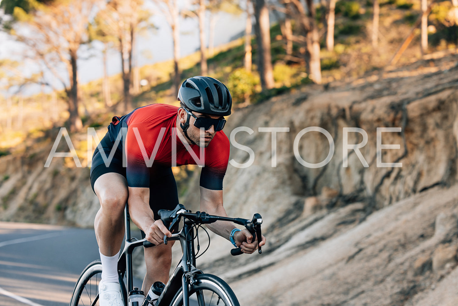 Professional cyclist going down a hill. Athlete in helmet and glasses riding road bike outdoors.