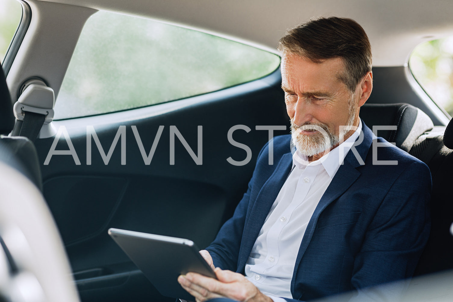 Senior entrepreneur typing on a digital tablet while sitting on the backseat in taxi	