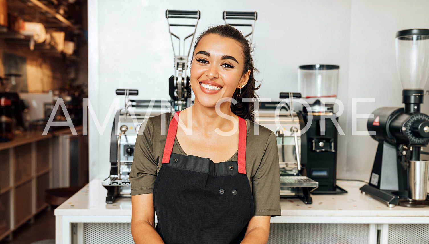 Happy waitress standing at coffee machine and looking at camera	