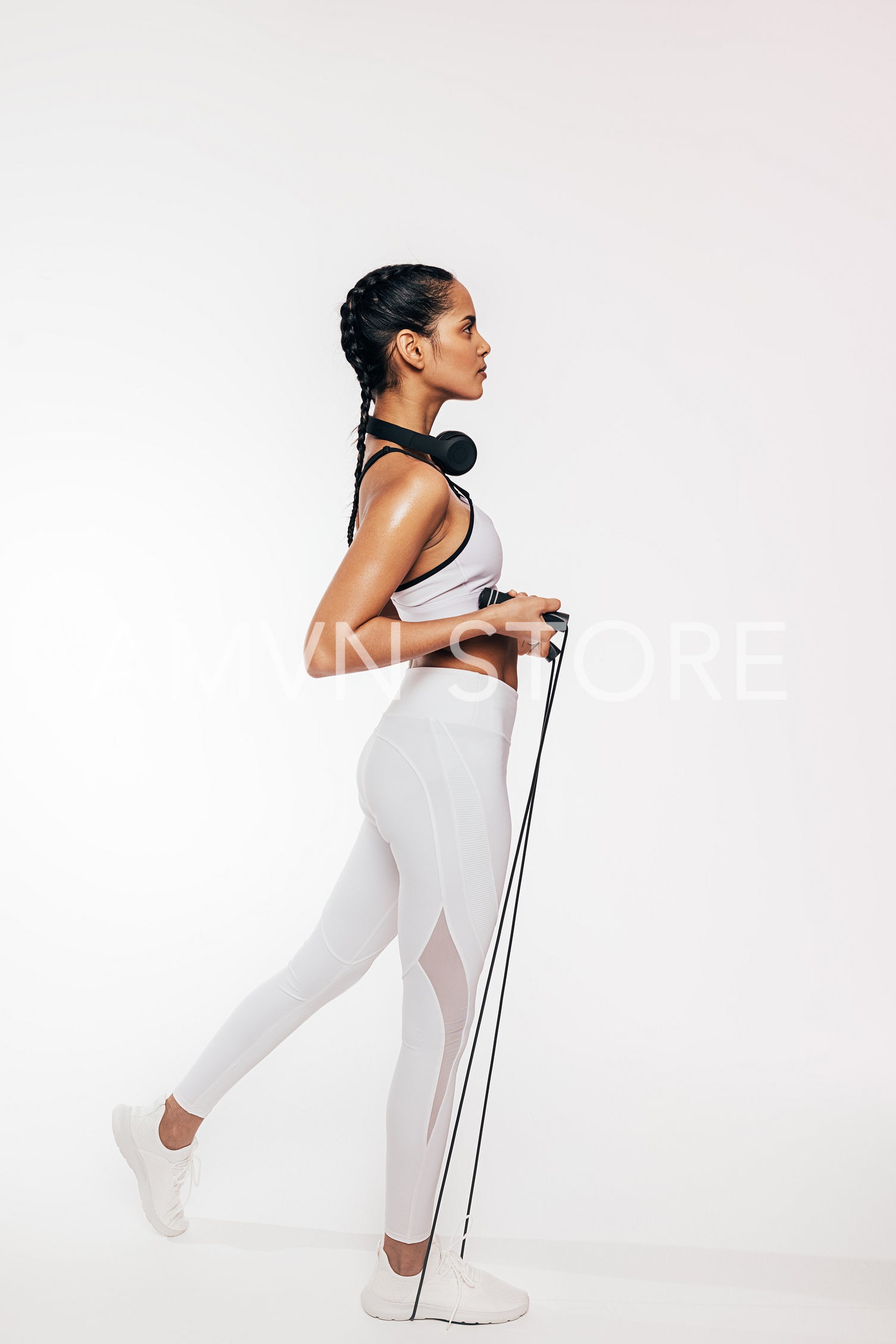 Side view of slim woman exercising with skipping rope over white background	