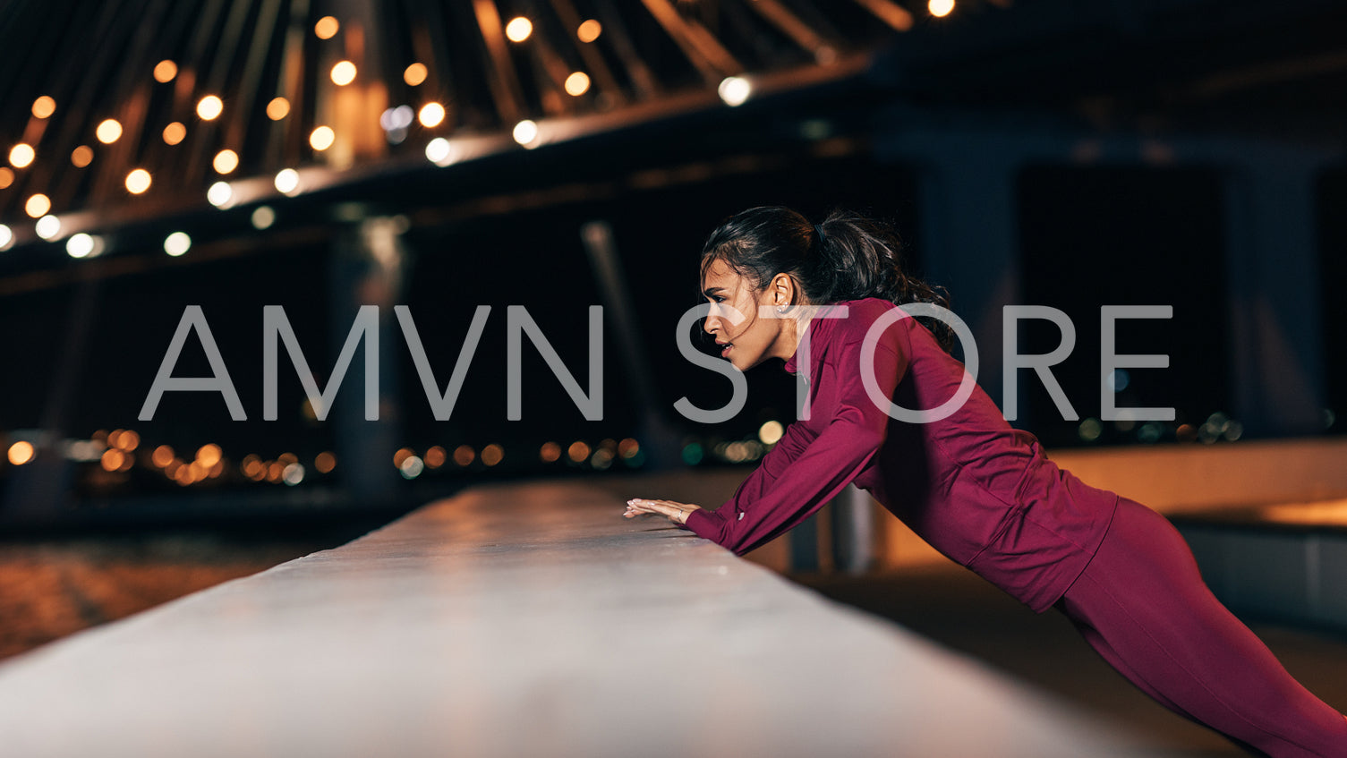 Side view of young middle east woman doing push-ups. Female athlete exercising at night outdoors.