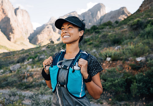 Smiling middle-aged female relaxing during a hike, enjoying the view. Female in hiking sportswear looking on mountains.