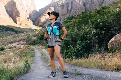 Woman runner looking away while standing on a abandoned road in valley