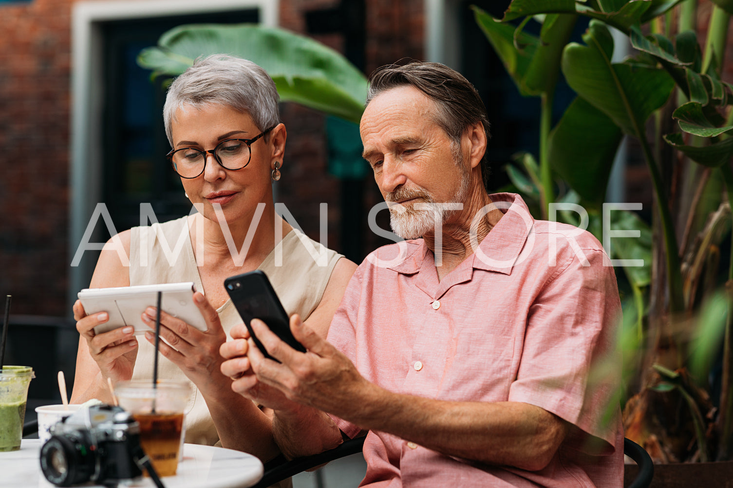 Mature couple using their smartphones while sitting together in an outdoor cafe