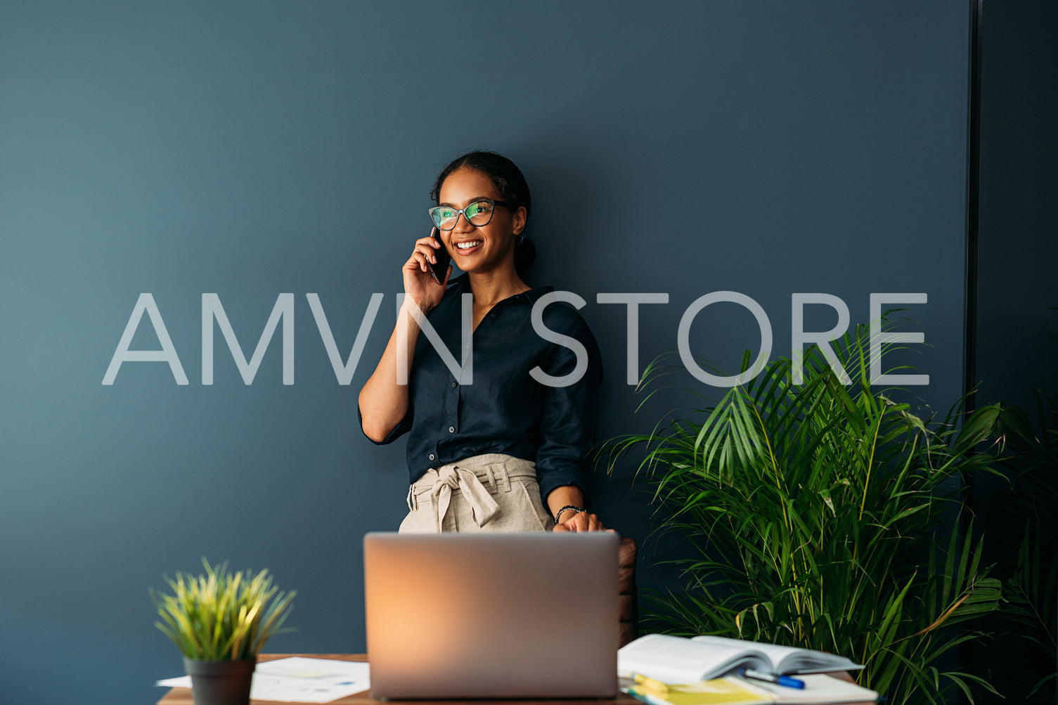 Smiling woman leaning on a blue wall. Businesswoman working from her apartment.