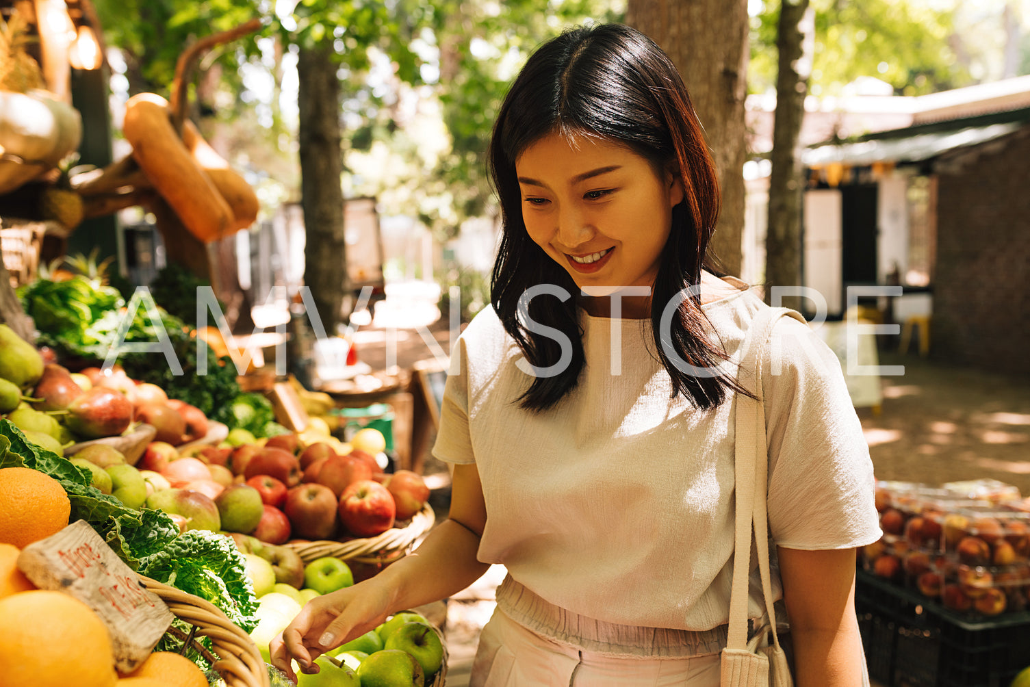 Smiling Asian woman at a stall on outdoor market. Female buy fruits on street market.