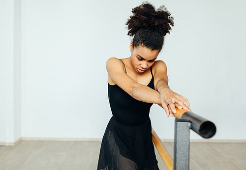 Mixed race woman in dancewear resting during exercises at the barre