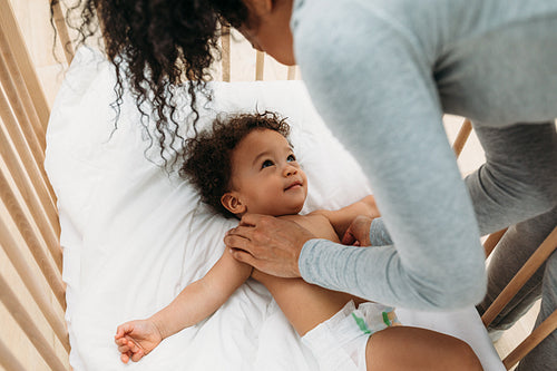 Mother putting her newborn baby boy into crib