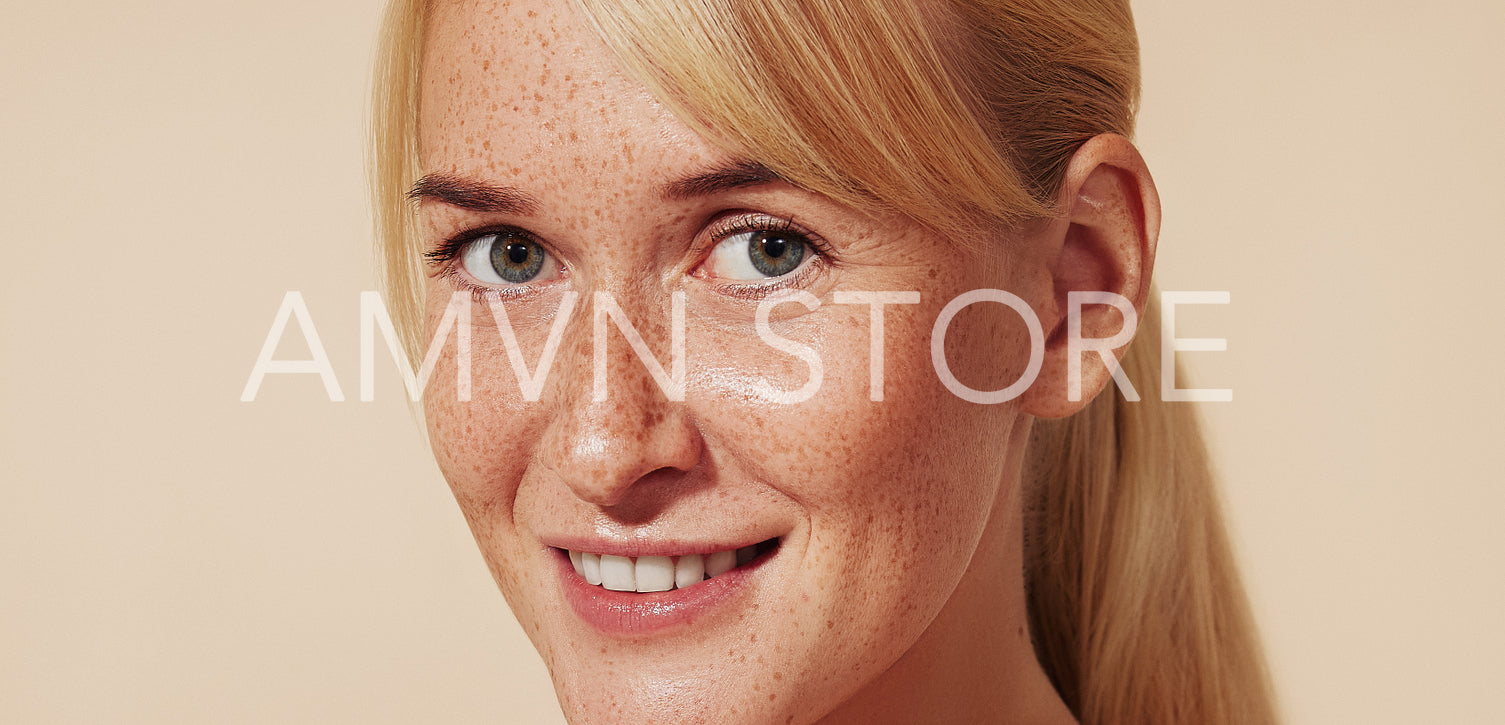 Close-up portrait of a smiling woman with blond hair and freckles. High-detailed portrait of a young cheerful female with naturally smooth skin.