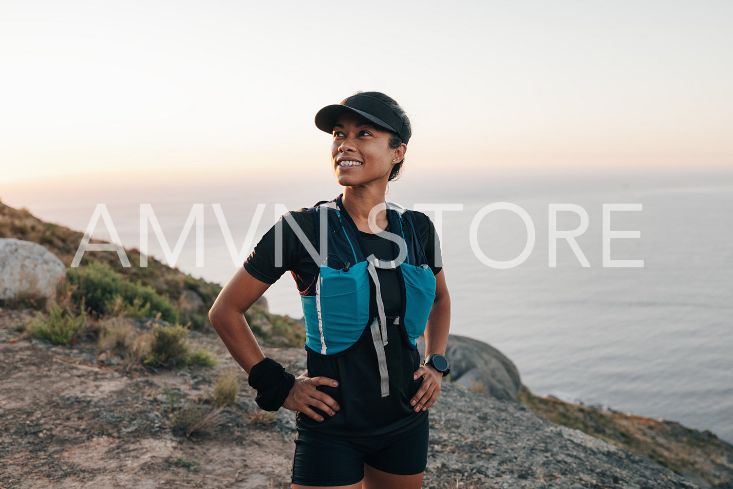 Portrait of a young woman in hiking attire standing in wild terrain and looking away at sunset