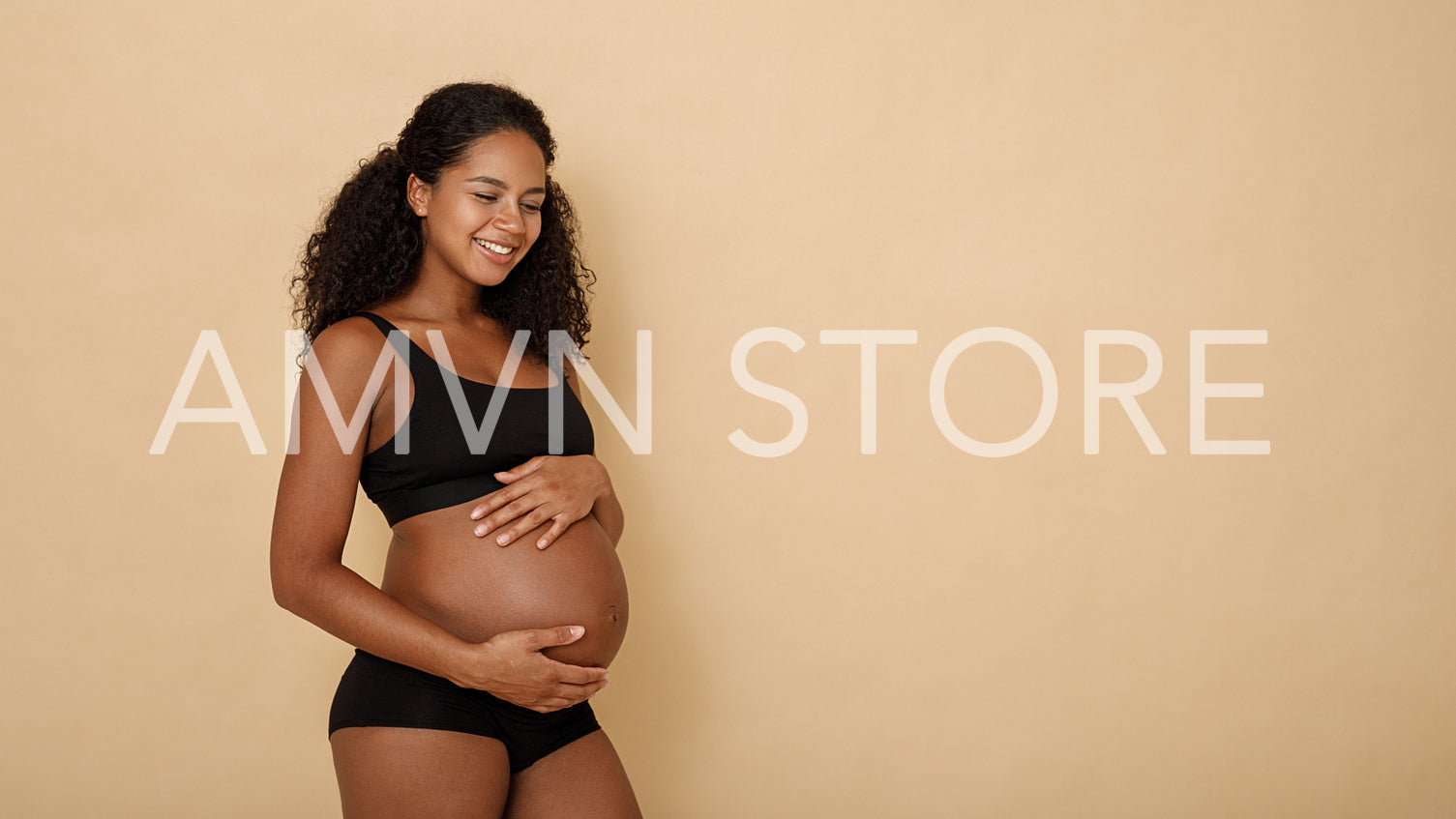 Side view of happy pregnant woman holding her belly	