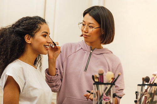 Makeup artist applying makeover on a model face in dressing room