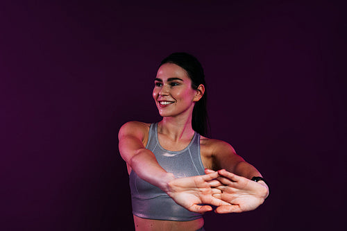 Close up of young smiling female stretching and flexing her hands over a magenta background in studio