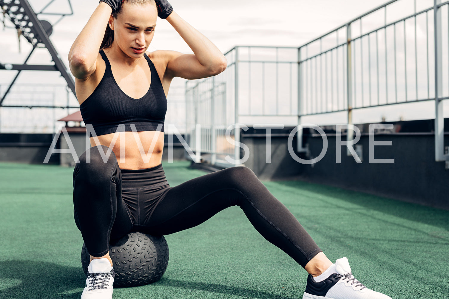 Young woman sitting on a medicine ball on a rooftop	
