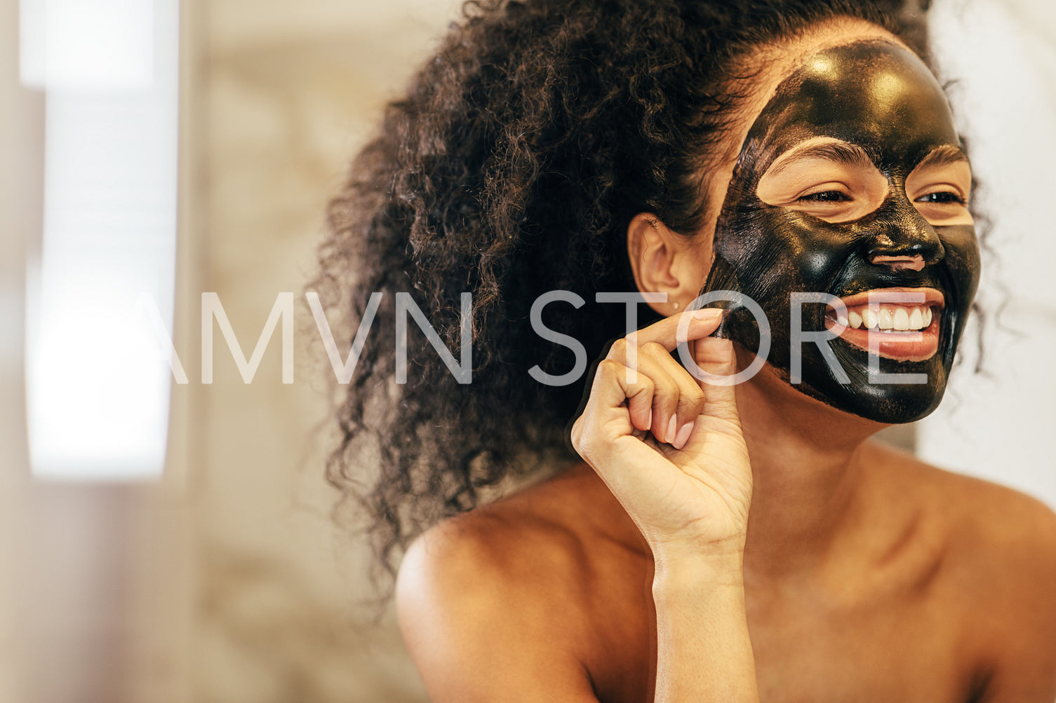 Smiling woman removing black cosmetic mask from her face	