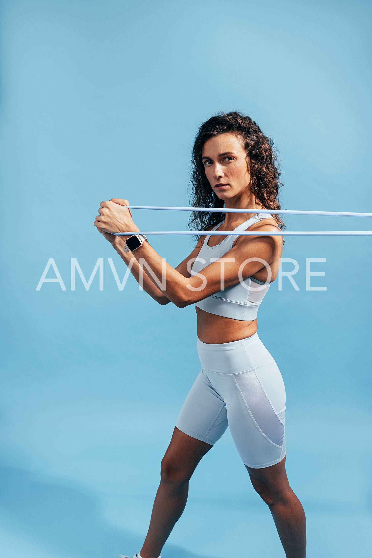 Muscular woman working out with resistance band on blue background