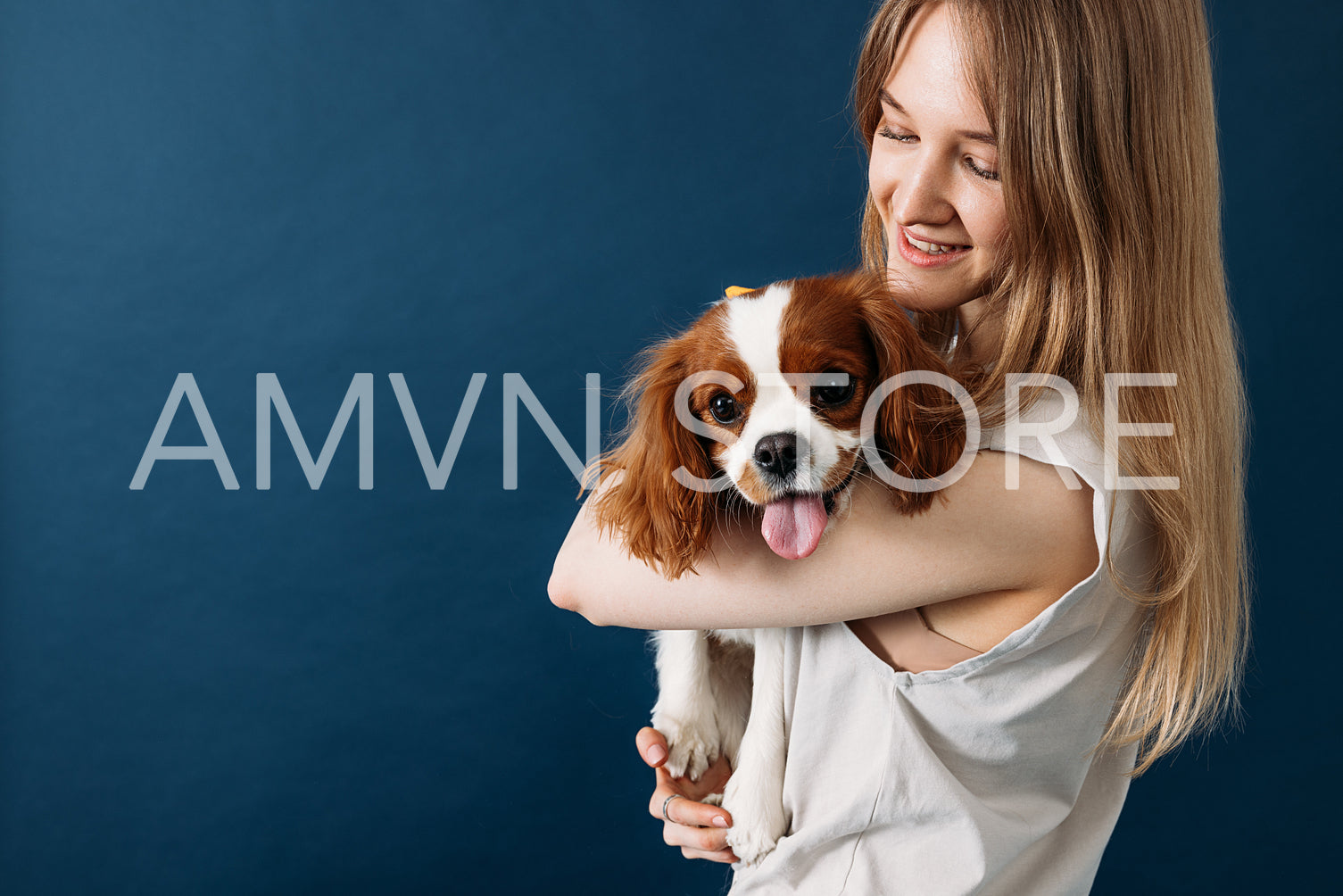 Young smiling pet owner holding her cute little dog in studio ag