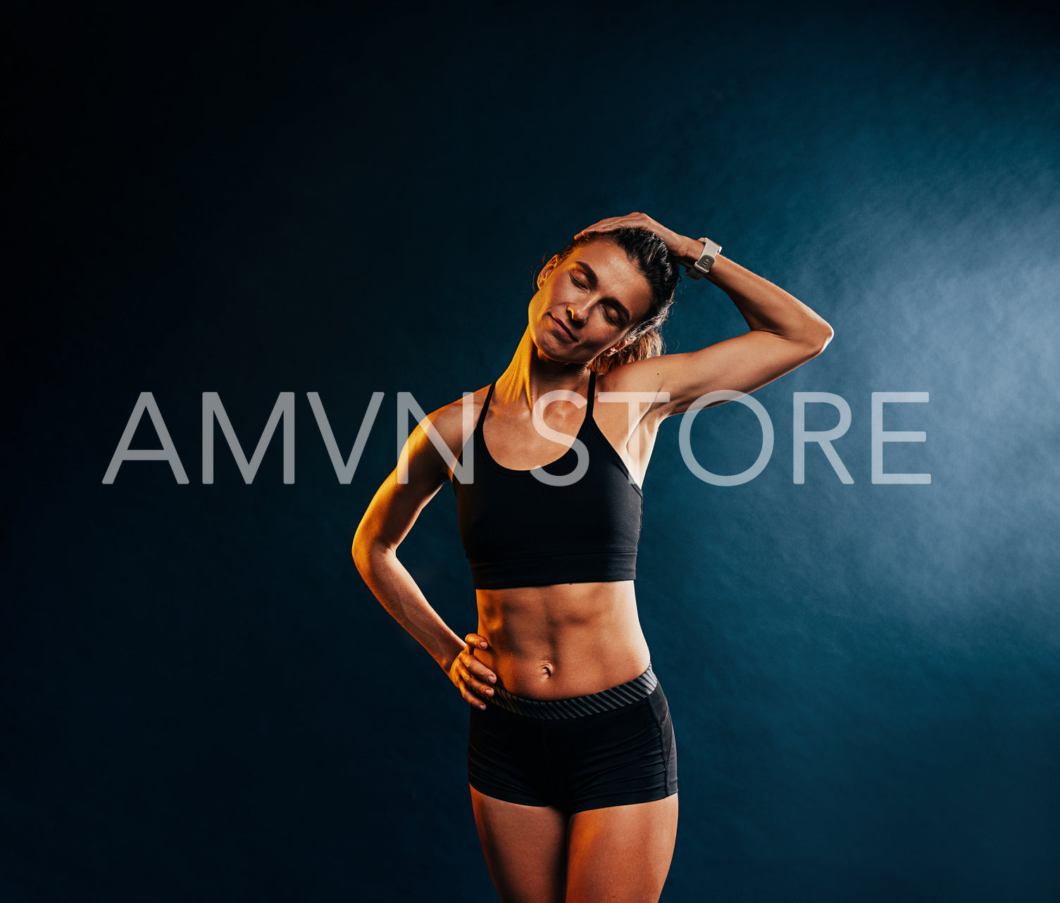 Young muscular woman warming up her neck before training against black background