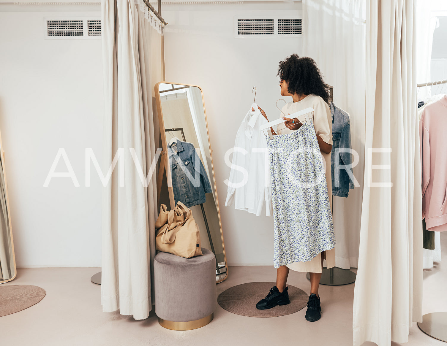 Young woman choosing clothes while standing in fitting room in a boutique