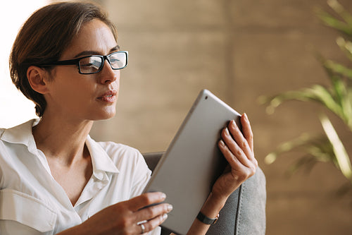 Close-up of a female with glasses and short hairstyle holding a digital tablet