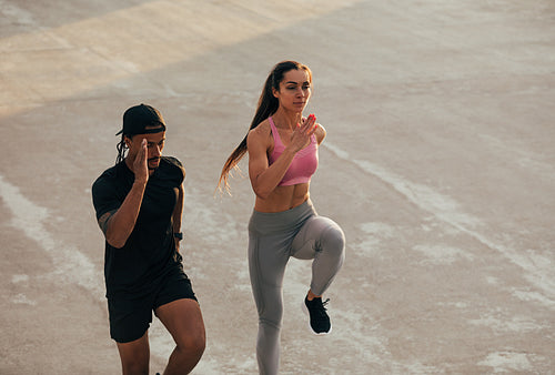 High angle of two athletes jumping together doing warming up before a run