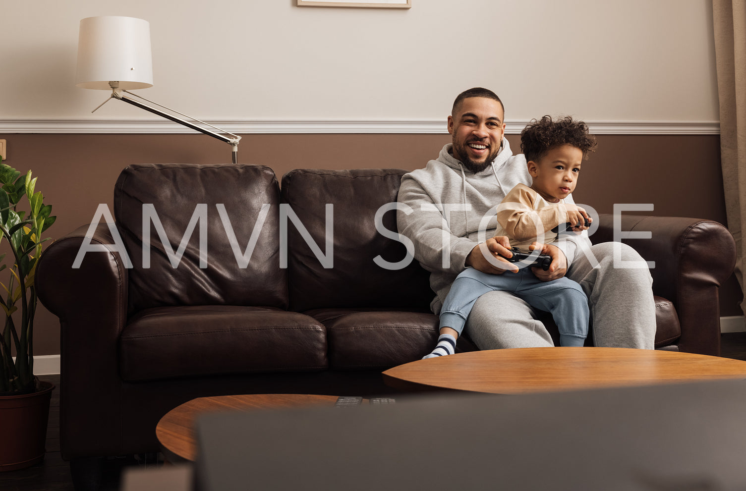 Little boy and his father having fun while playing video games at home