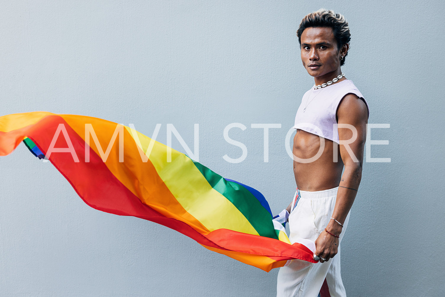 Handsome male with rainbow flag looking at camera at grey wall