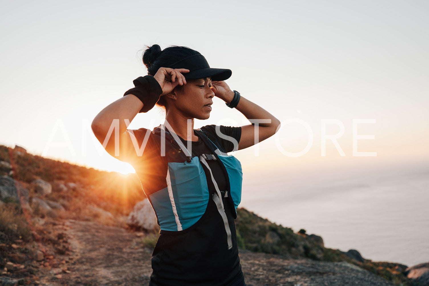 Trail runner taking a break. Woman holding her hat during hike at sunset.