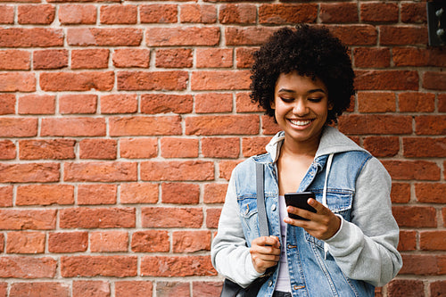 Happy hipster girl looking at her smartphone. Woman sends a message from cell phone.