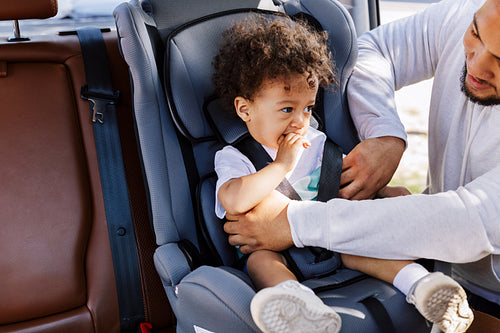 Young man fasten his son in a baby seat