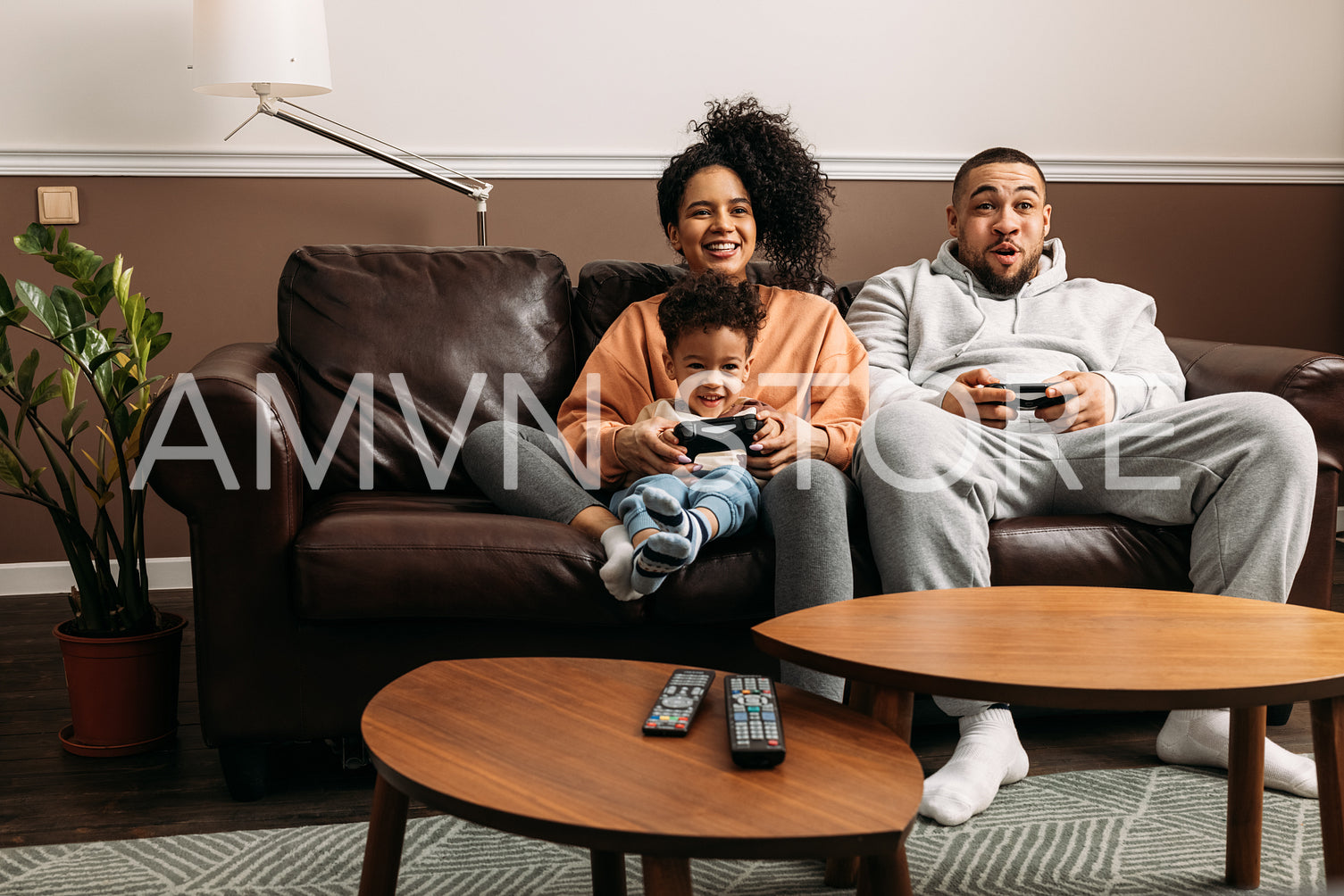 Happy parents with son playing video game. Family of three spending time together on couch at home.