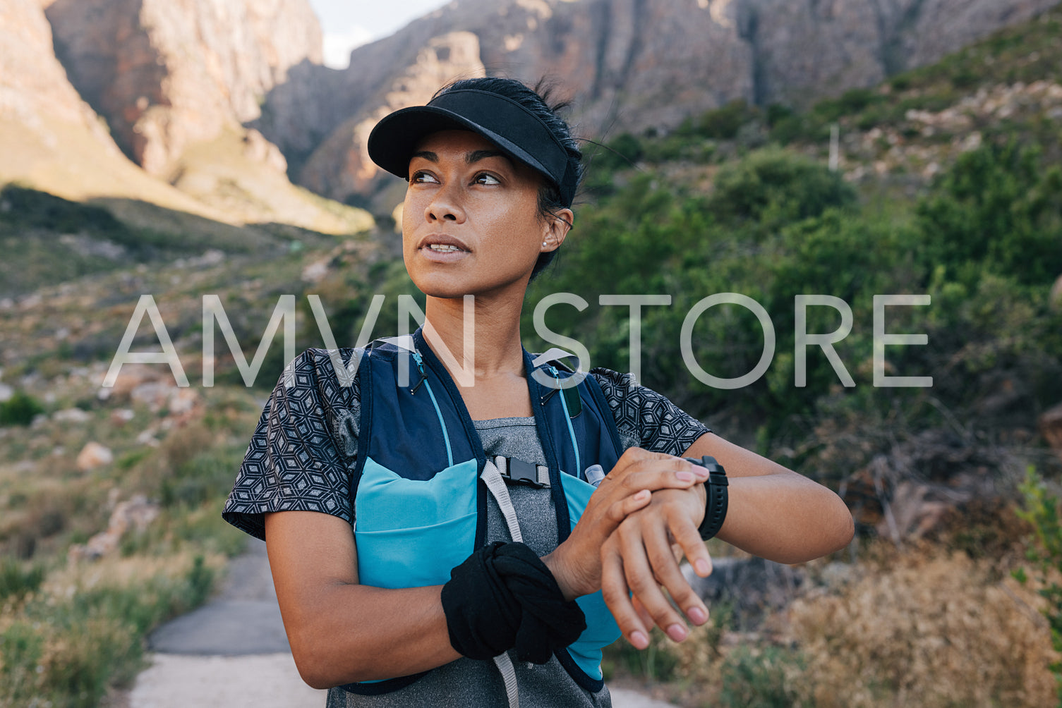 Portrait of healthy trail runner checking smart watch. Woman in sportswear taking a break during hike looking away.