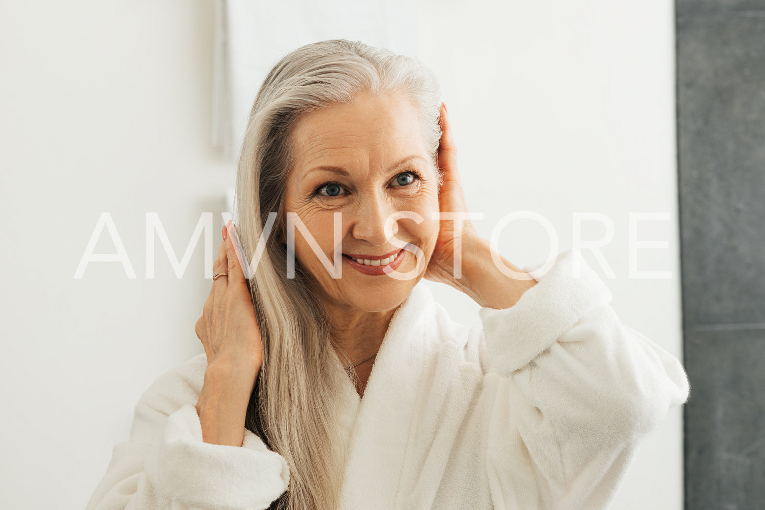 Portrait of a senior woman adjusting her grey hair while looking at the bathroom mirror