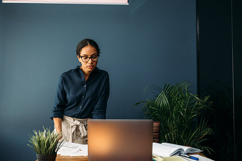 Serious businesswoman looking on a laptop screen while standing at a table