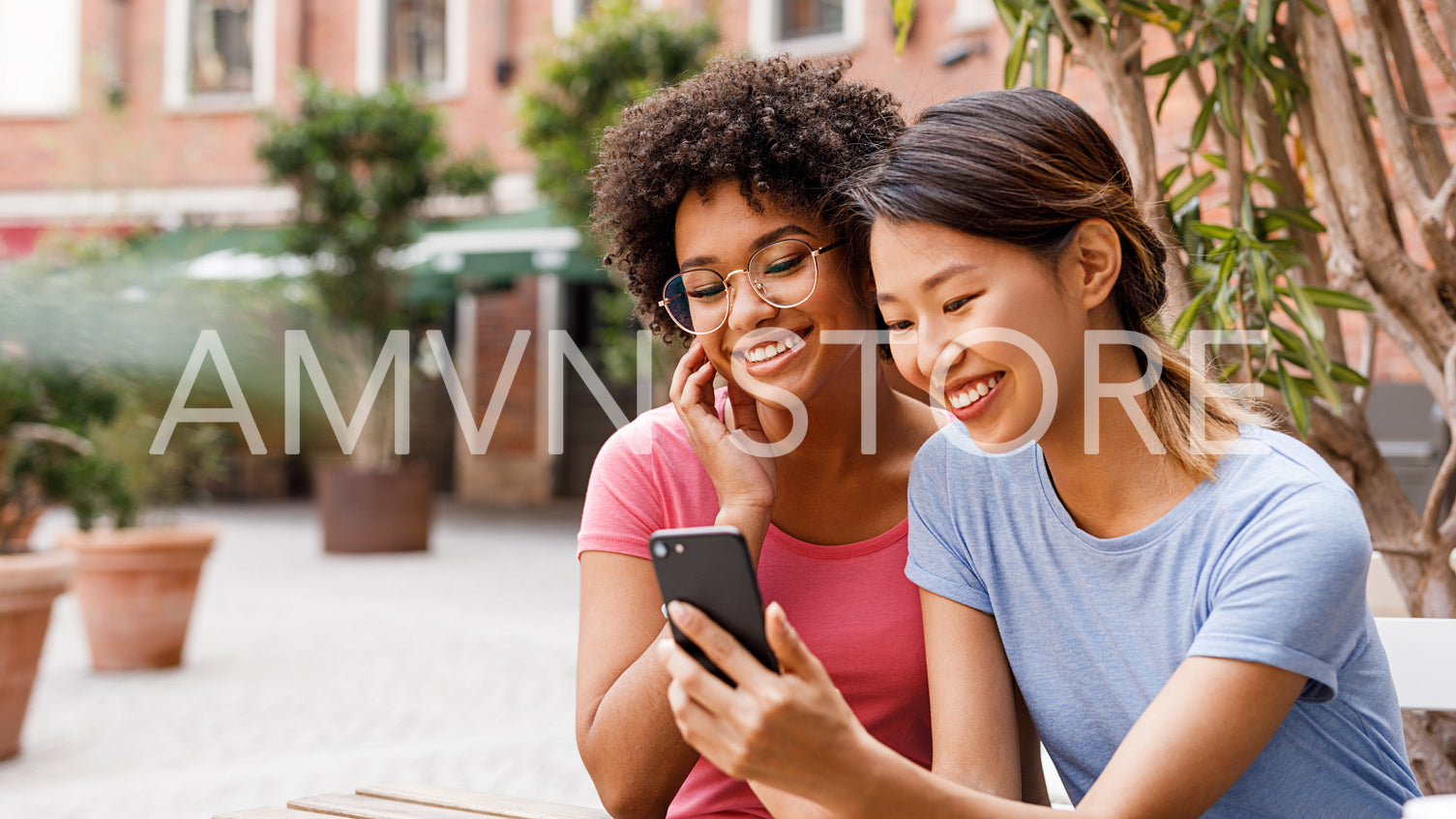 Two female friends live streaming from outdoor cafe	