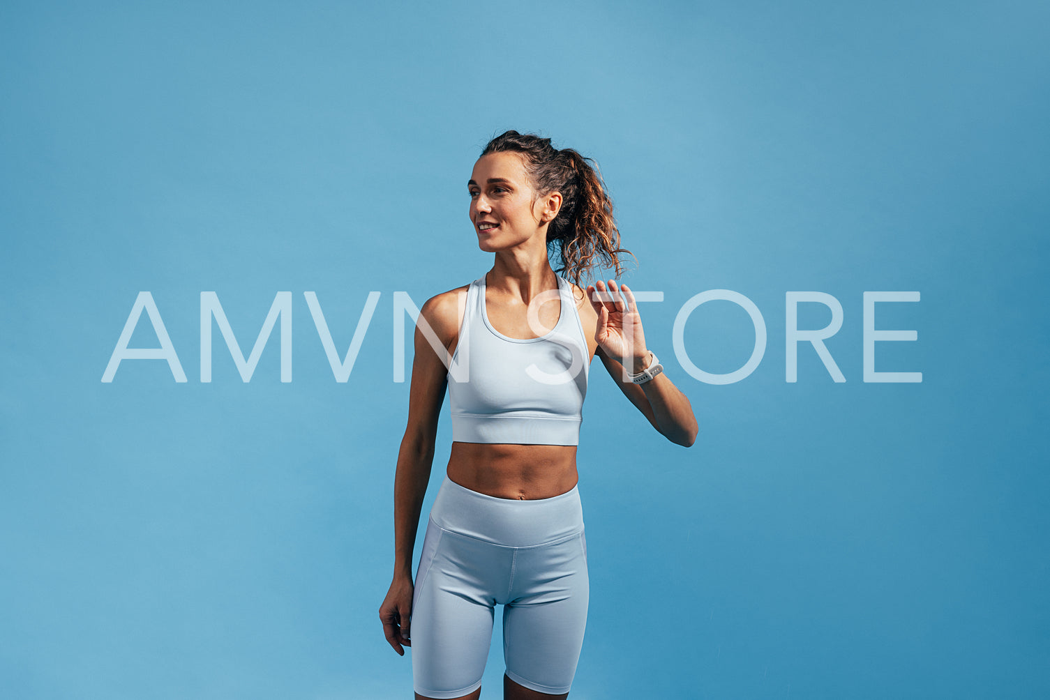 Young woman with slim healthy body standing against a blue wall