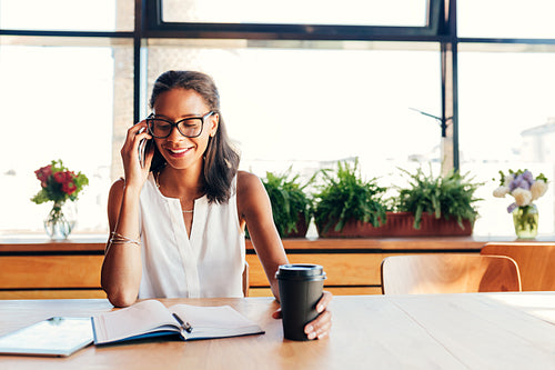 Happy businesswoman talking on smartphone. Female entrepreneur in cafe.