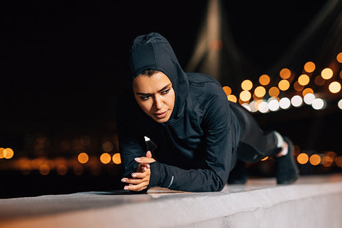 Young athlete doing plank position while exercising outdoors at evening