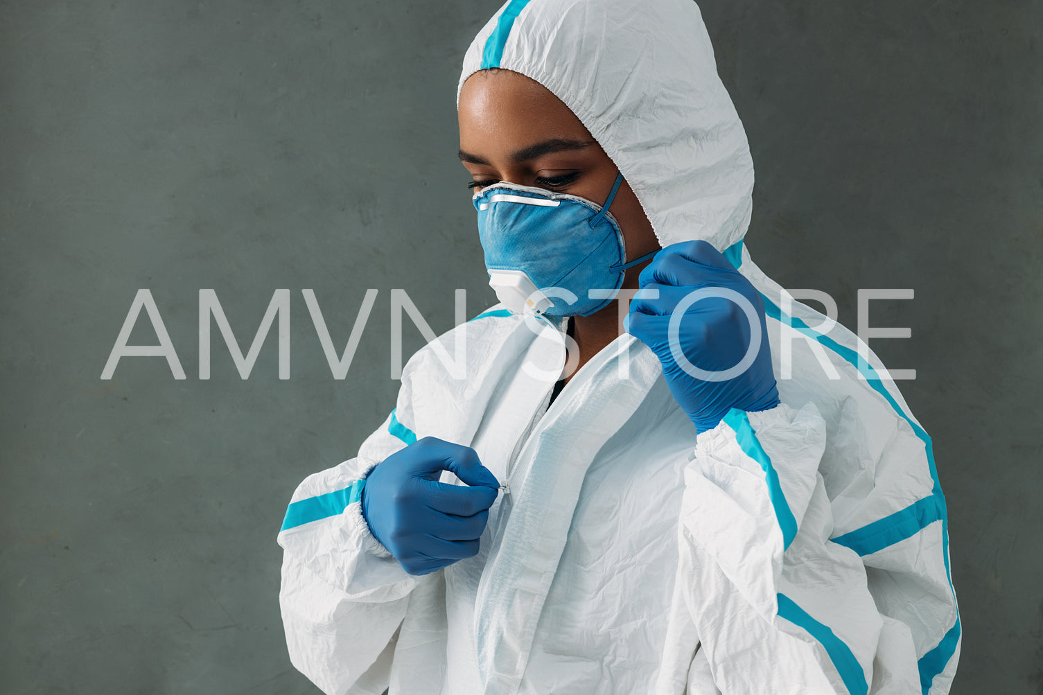 Female nurse in medical respirator zipping white protective suit