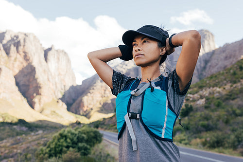 Young woman hiker in cap relaxing while standing in valley