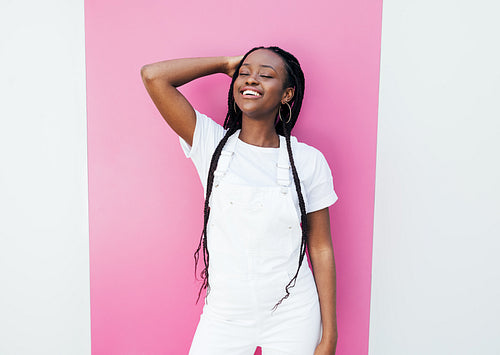 Positive woman with closed eyes wearing white clothes adjusting hair