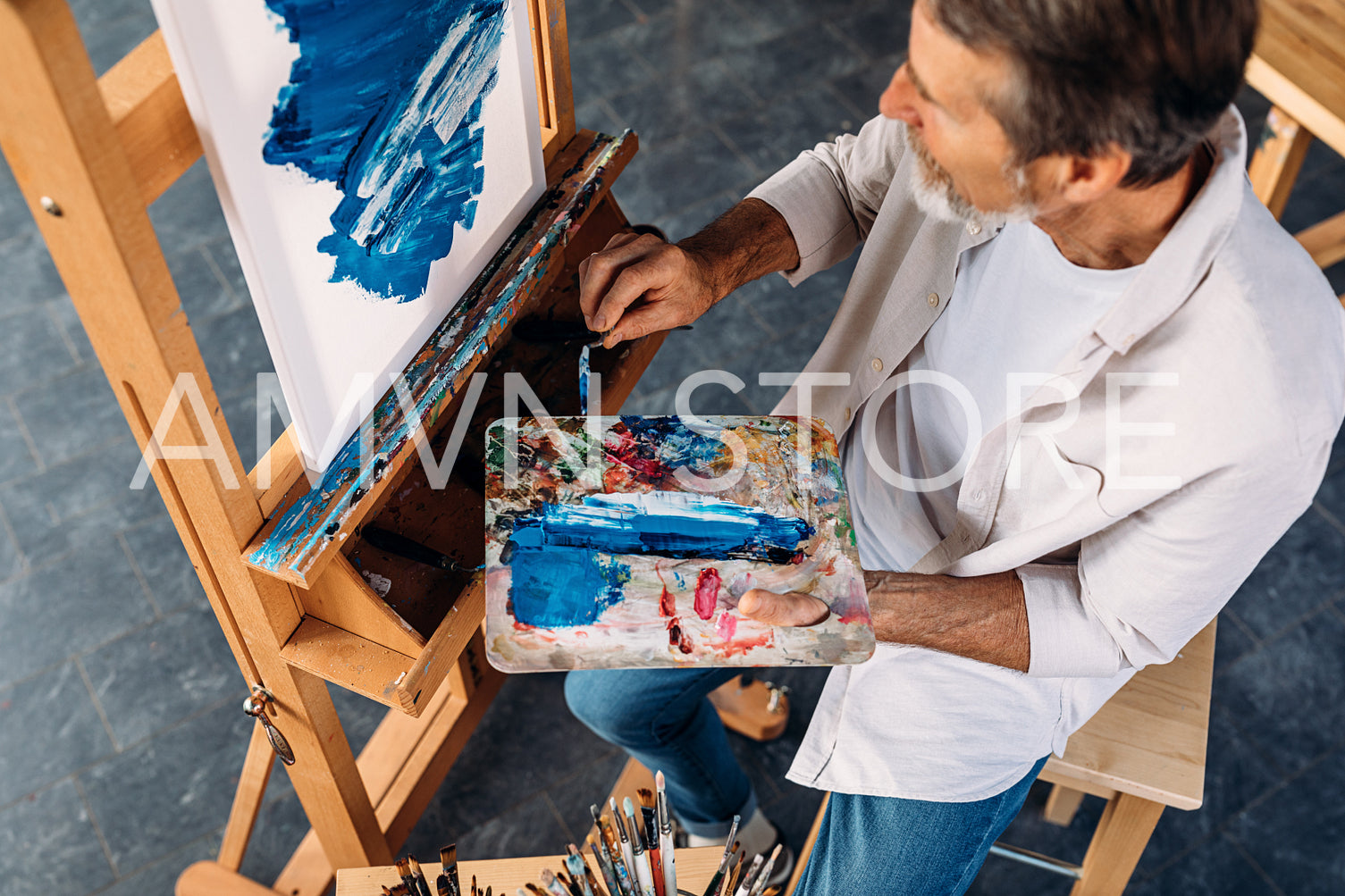 High angle view of male artist holding palette and paint knife	