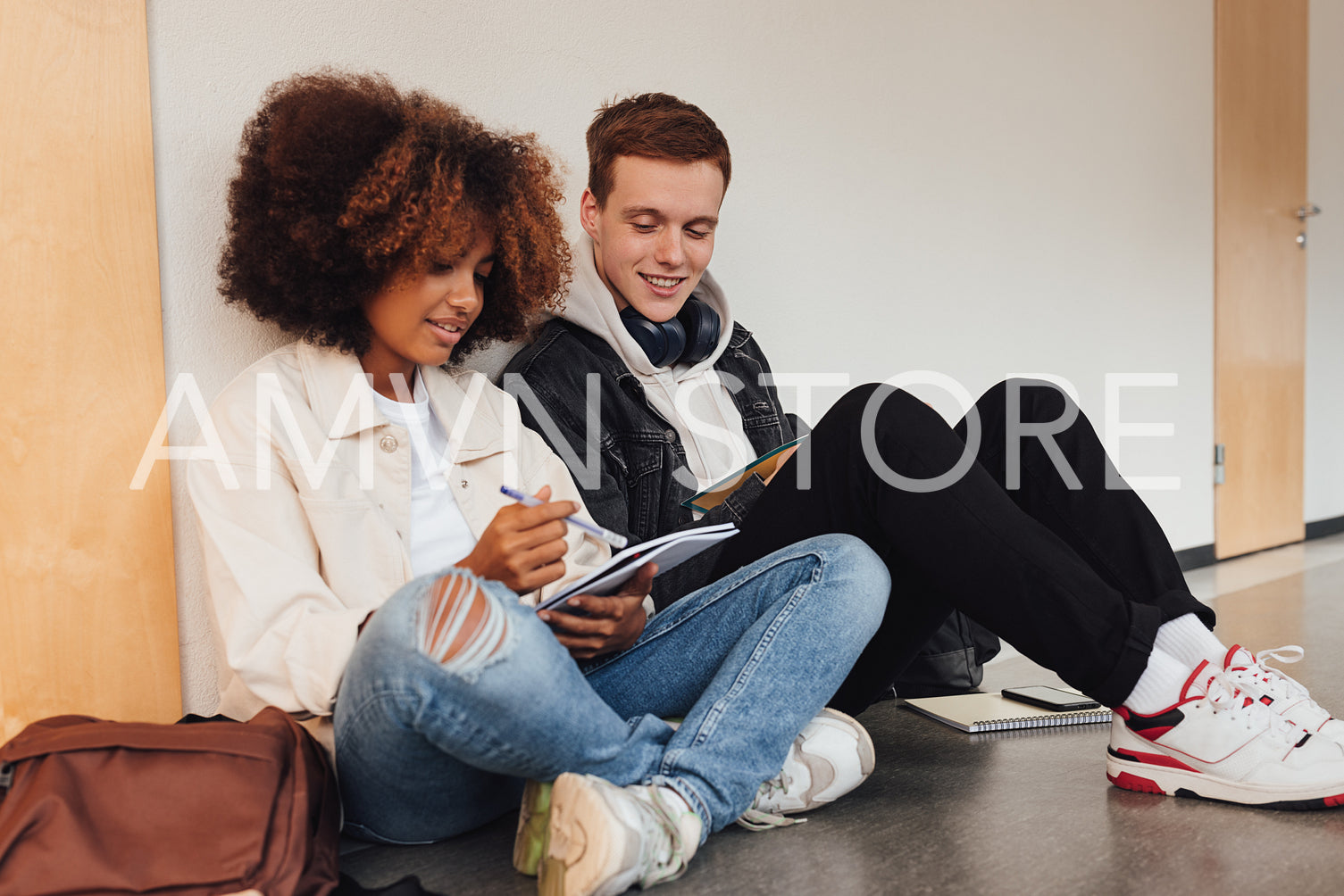 Two students sitting on a floor and preparing their assignments