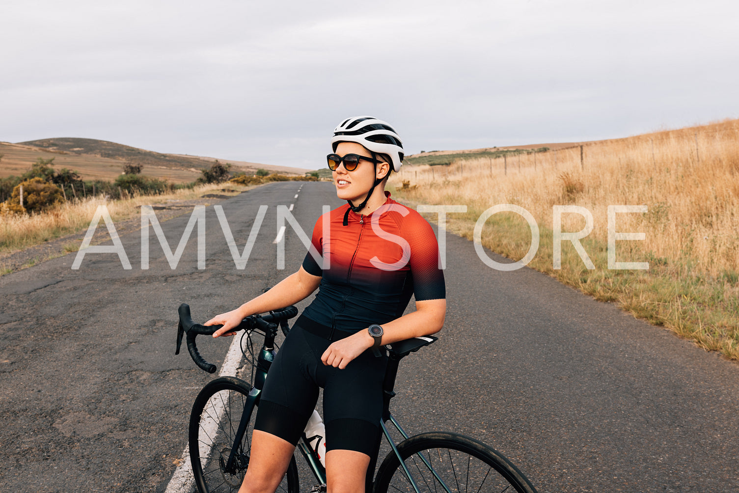 Portrait of female bicycle rider taking a break on country road sitting on bike