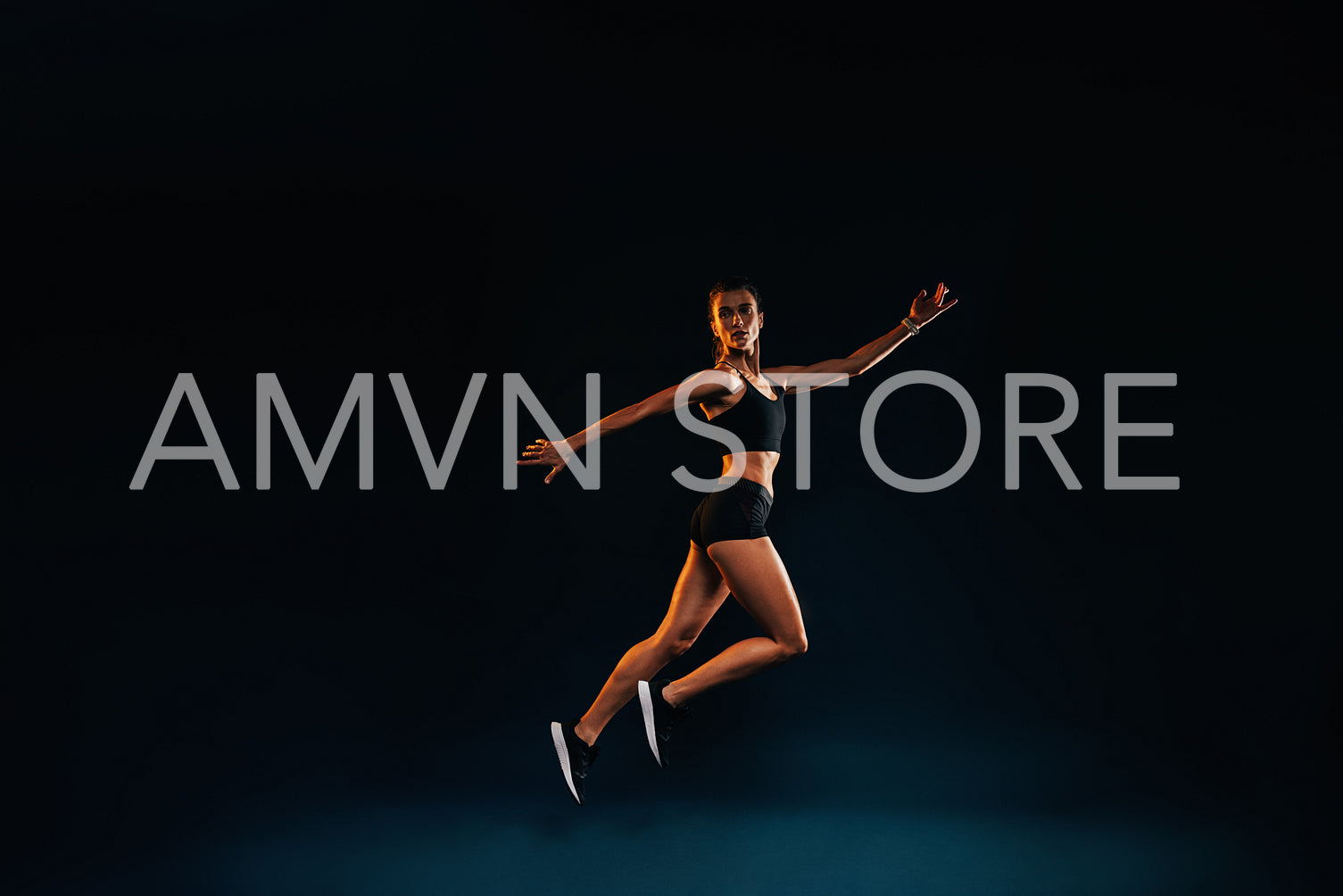 Slim woman working out on black background. Female athlete doing jumps in studio.