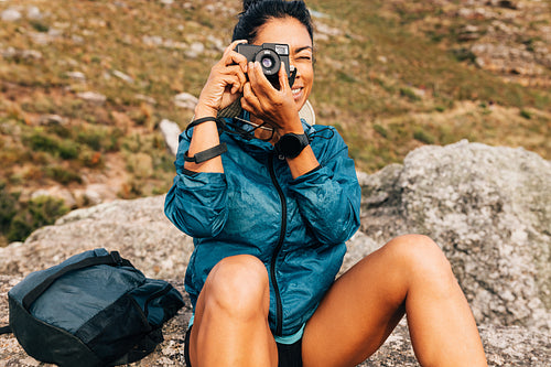 Woman hiker filming scenery while taking a break on a hill durin