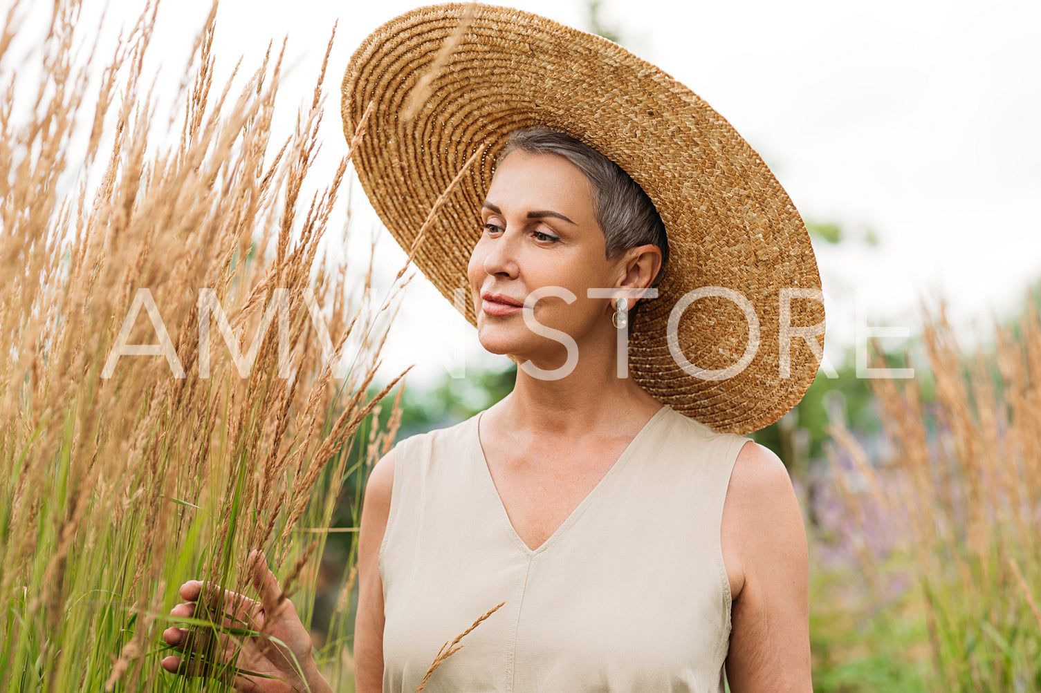 Aged woman in a straw hat on the field at summer