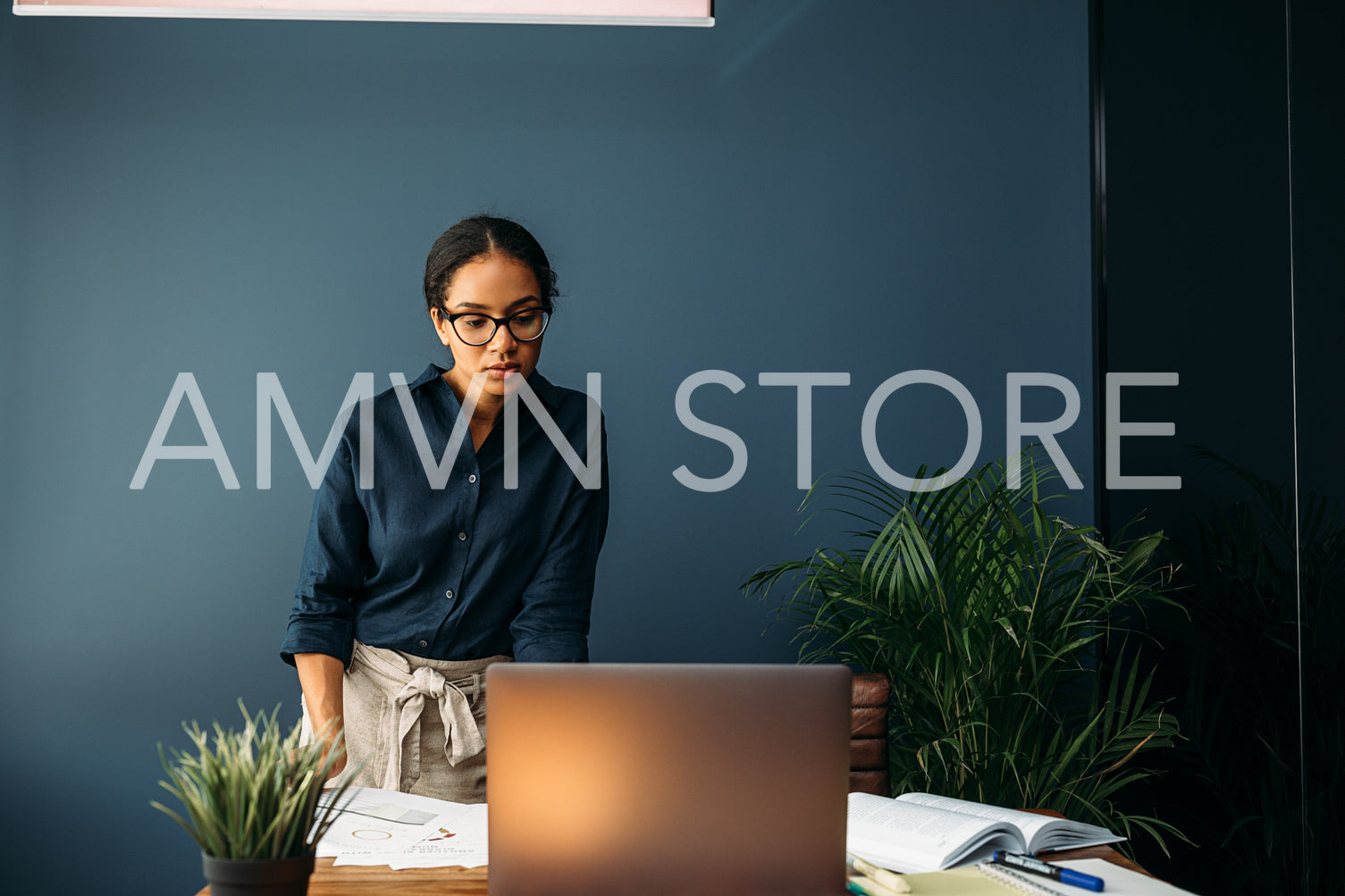 Serious businesswoman looking on a laptop screen while standing at a table	