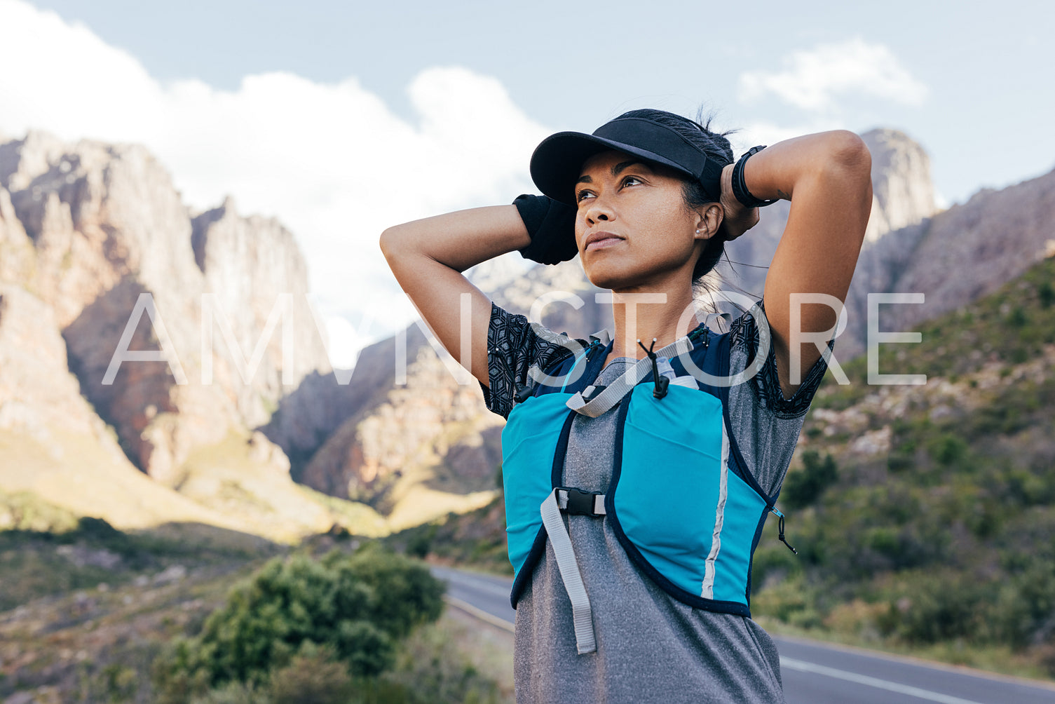 Young woman hiker in cap relaxing while standing in valley